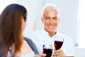 Senior man with holding a glass of wine indoors