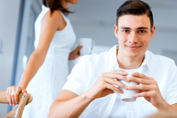 Happy young man with cup of tea or coffee