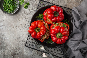red bell peppers stuffed with meat, rice and vegetables on cast iron pan