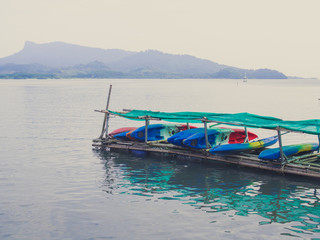 Fototapeta na wymiar Colorful fiberglass kayaks on outdoor storage in the sea