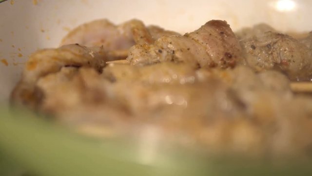 Frying a pork skewers in pan on gas stove, made of white meat and bacon