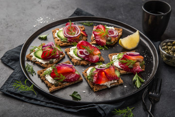 healthy sandwiches with wholegrain rye crisp bread, cream cheese, beet cured salmon and cucumber