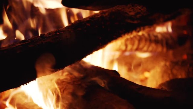 Close up and slow motion view of burning firewoods, bright firecamp with sparks