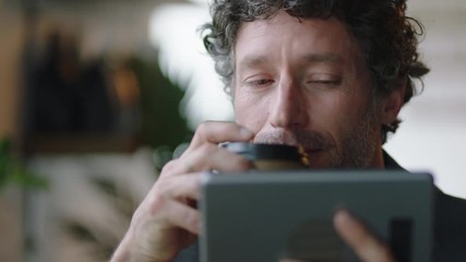 attractive caucasian businessman in cafe using tablet computer watching online entertainment reading social media messages enjoying drinking coffee relaxing - Powered by Adobe