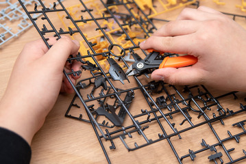 A boy's hand assembling plastic models using tools.