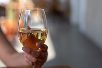 Woman holding glass of white wine elegantly 