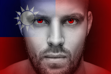 Portrait of a young serious man in whose eyes the reflected national flag of Taiwan, against an isolated black background and flag