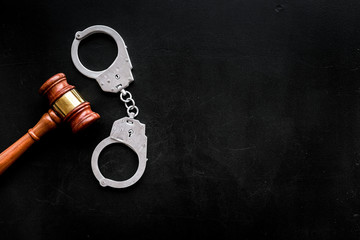 Crime concept. Metal handcuffs near judge gavel on black background top view space for text