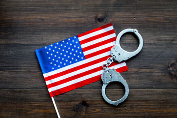 Violation of law, law-breaking concept. Metal handcuffs on American, USA flag on dark wooden...