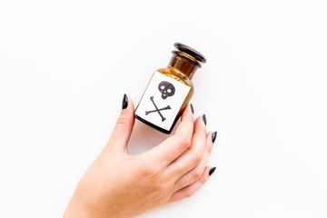 Dangerous addictions, dangerous entertainment. Poison. Female hand hold bottle with skull and crossbones on white background top view copy space