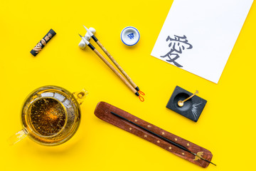 Lesson of calligraphy concept. Paper with hieroglyph near writing accessories, teapot and cup of...