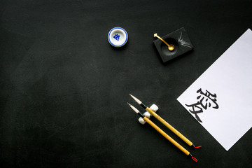 Chinese or japanese calligraphy concept. Hieroglyph near traditional written accessories on black...