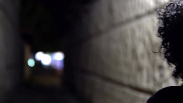 Traking a woman model walking in dark alley at night, narrow dirty corner, street in the old town, cinematic dof