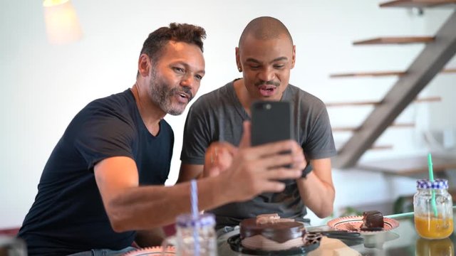 Gay Couple talking with distance people on a video chat celebrating birthday party