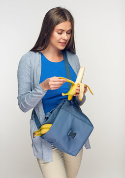 portrait of woman with lunch bag eating banana.