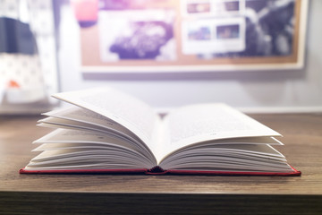 Closeup the book at wood desk with open book in class room background.