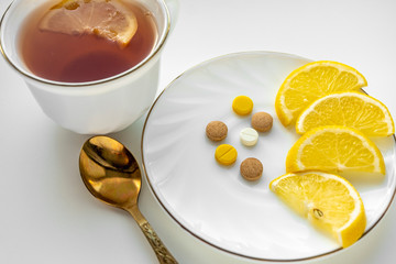 Tea with lemon and pills on the white table. The concept of colds.