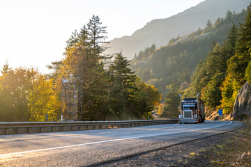 Big rig classic semi truck transporting cargo on the winding autumn road in Columbia River Gorge