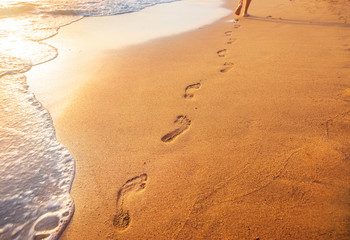 beach, wave and footprints at sunset time