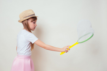 little and beautiful blonde girl in a straw hat holds a butterfly net in her hand and catches butterflies studio white background.Cheerful female kid playing