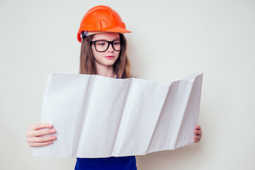 Teenager girl with plan holding urban designer paper in a construction helmet hard hat and glasses