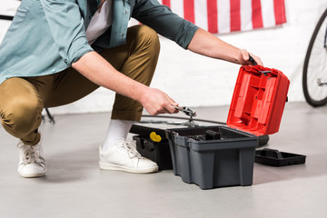 cropped image of man putting adjustable wrench in tools box