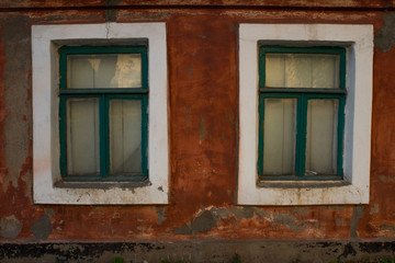 old red house with two green old windows in the street