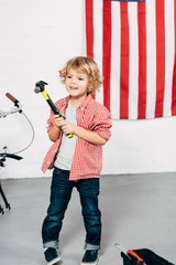 selective focus of happy adorable boy holding hammer