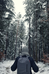 Winter tourism. Male traveler with a backpack in the winter forest. Man on a winter forest road