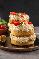 Obraz na płótnie Canvas Victoria sponge cake with strawberries, jam and whipped cream on dark background. Copy space.