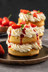 Victoria sponge cake with strawberries, jam and whipped cream on dark background. Copy space.