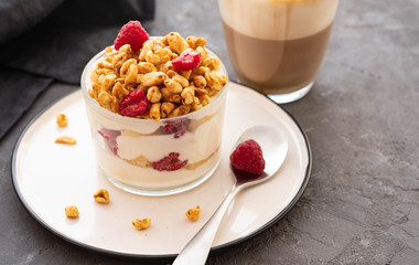 Fresh yoghurt with rasberries and coffee in clear glass. Raspberries in white bowl. Healthy morning breakfast.