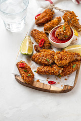Chicken nuggets with sauce and pepper on a white board. Copy space.