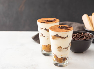 Homemade tiramisu, traditional Italian dessert in glass on white table. Copy space.