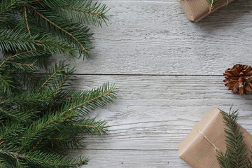Fir tree branches, cone and eco packed gift boxes. Christmas background concept. Copy space, white wooden boards, border