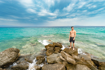 Sseascape with alone man on the rocks at isolated island rocks and horizon