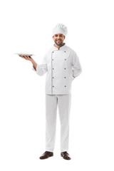 happy young chef holding empty plate and looking at camera isolated on white