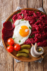 traditional Labskaus recipe of potato, corned beef and beet with a fried egg and herring close-up on a plate. Vertical top view