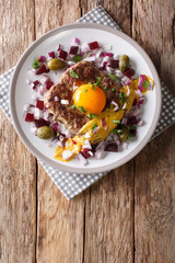 Delicious Danish Pariserbof served with raw egg yolk, mustard and vegetables close-up on a plate. Vertical top view