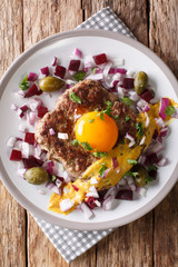 Danish cuisine: Parisian steak or Pariserbof with vegetables and mustard close-up on a plate. Vertical top view