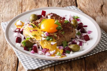 Delicious Danish Pariserbof served with raw egg yolk, mustard and vegetables close-up on a plate. horizontal