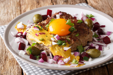 Traditional Danish steak Pariserbof with egg yolk and mustard, served with onions, capers and beet close up. horizontal