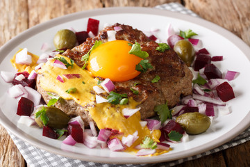 Freshly Cooked Danish Pariserbof Steak with egg, vegetables and mustard close-up on a plate....