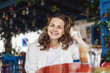 Portrait of beautiful cute cool happy smiling girl at a table in an outdoor cafe