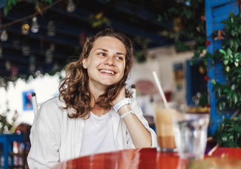 Portrait of beautiful cute cool happy smiling girl at a table in an outdoor cafe