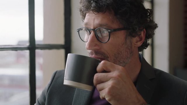 portrait happy mature business man drinking coffee at home enjoying relaxed morning looking out window planning ahead thinking successful caucasian male smiling wearing glasses in apartment loft