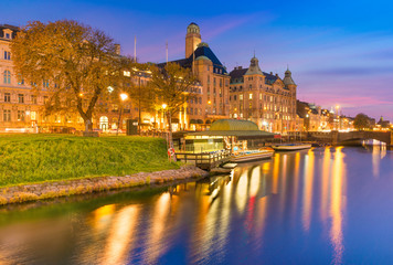 Fototapeta na wymiar Beautiful sunset in Malmo, Sweden. Picturesque evening cityscape. Old historical buildings, canal with boats at the wharf, colorful reflections in water