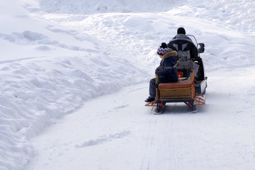 a man riding on a snowmobile with the kids .