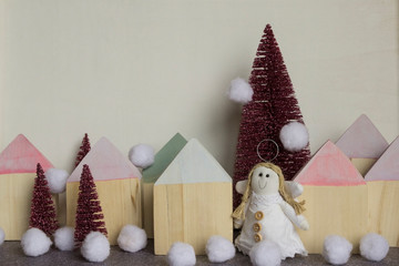Engel in weissem Kleid zwischen Häusern und pink Christbäumen im Schnee
