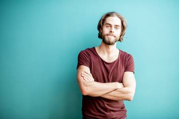 Fototapeta premium Portrait of a young caucasian bearded man with long hair dressed in t-shirt on the colorful background